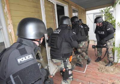 Police use a battering ram to force entry into the front door.