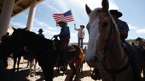 A protester waves the U.S. flag near the Bureau of Land Management's base camp where seized cattle, that belonged to rancher Cliven Bundy, are being held at near Bunkerville