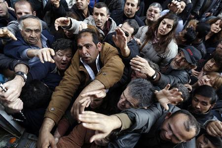 People reach out to take fruits and vegetables distributed for free by farmers during a protest against high production costs outside the Agriculture Ministry in Athens