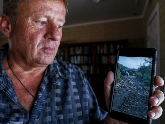 Mick Ohman shows a picture of his broken down car.